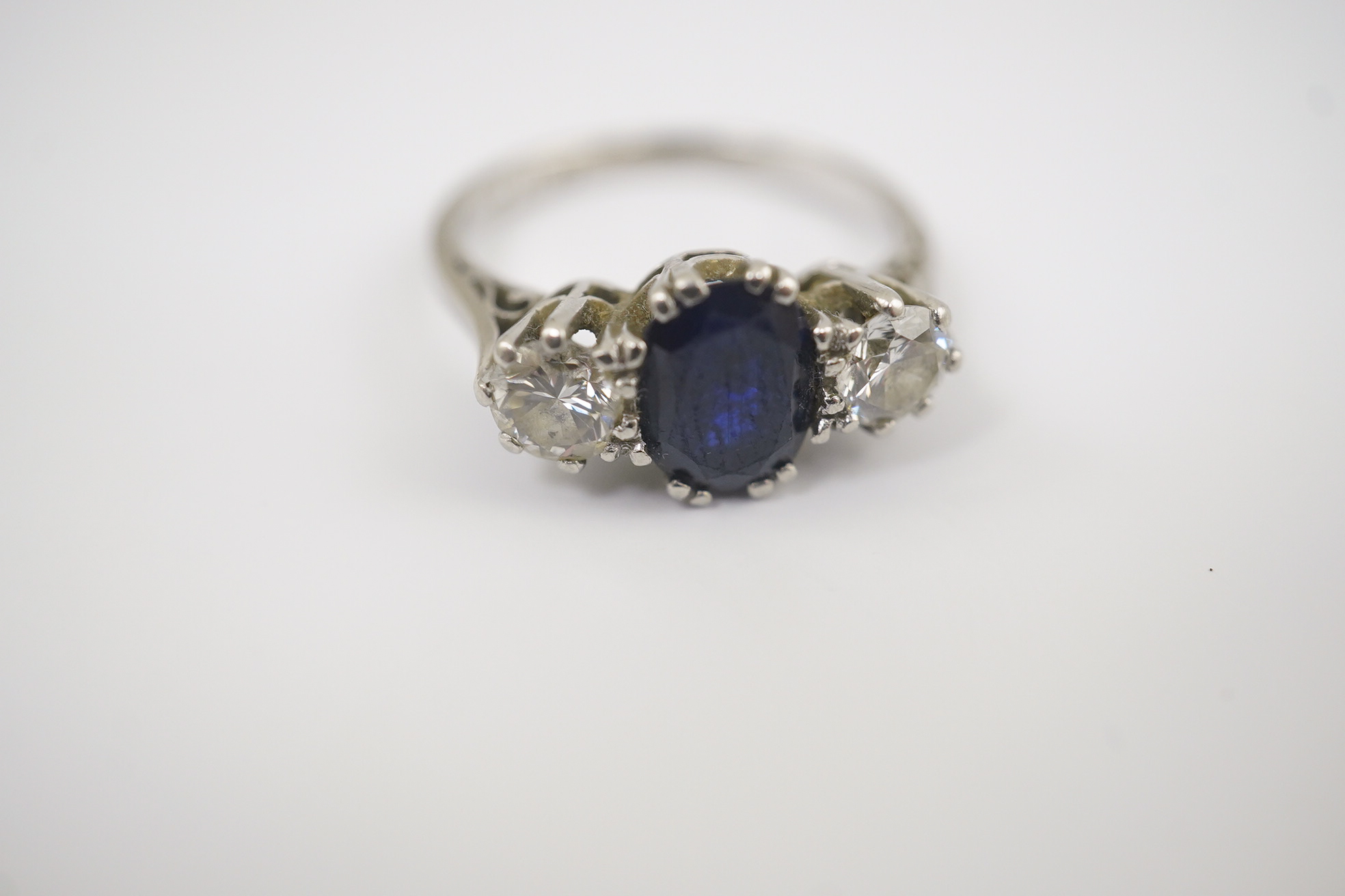 An 18ct white gold and platinum, single stone oval cut sapphire and two stone round cut diamond set ring